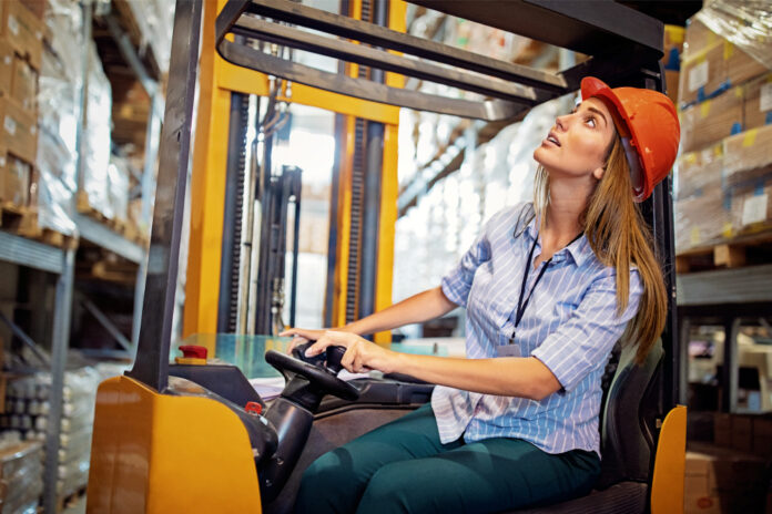 Woman is working with forklift in a warehouse