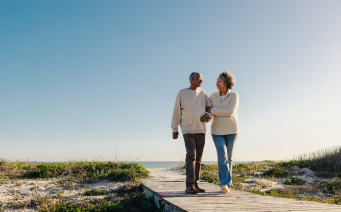 Romantic senior couple walking down a foot bridge at the beach