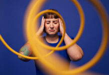 Lawaai op het werk mogelijk gekoppeld aan depressie en hartinfarct Woman with head in hands standing with eyes closed behind spiral cables against blue background