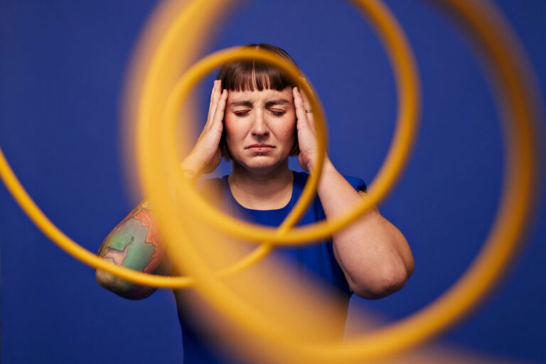 Lawaai op het werk mogelijk gekoppeld aan depressie en hartinfarct Woman with head in hands standing with eyes closed behind spiral cables against blue background